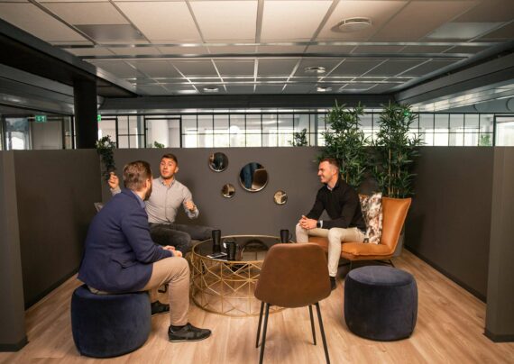 Tre menn sitter i et loungeområde i et kontorfellesskap
