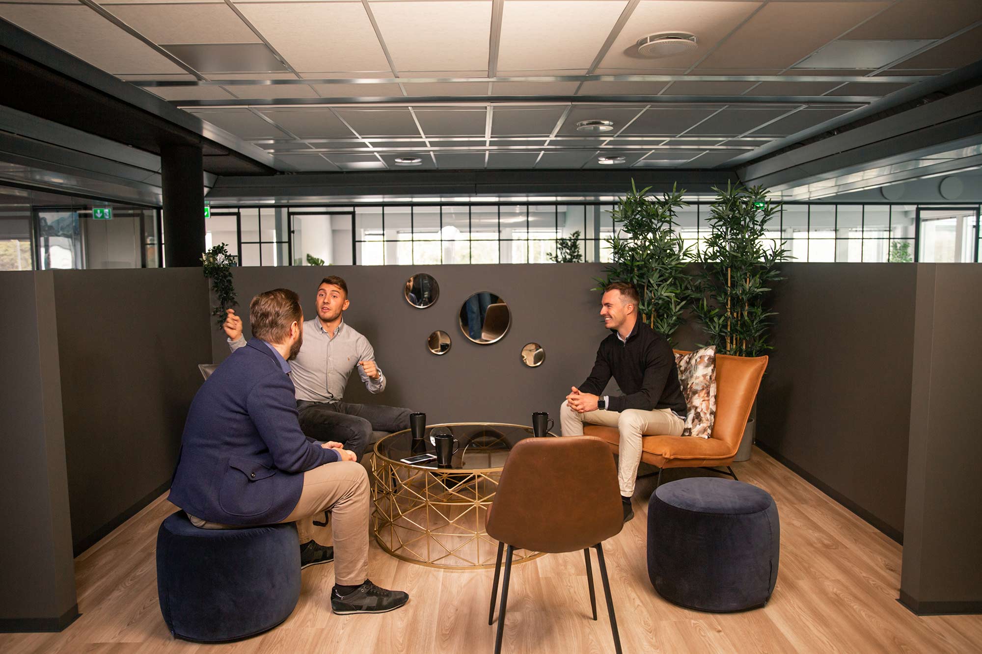 Tre menn sitter i et loungeområde i et kontorfellesskap