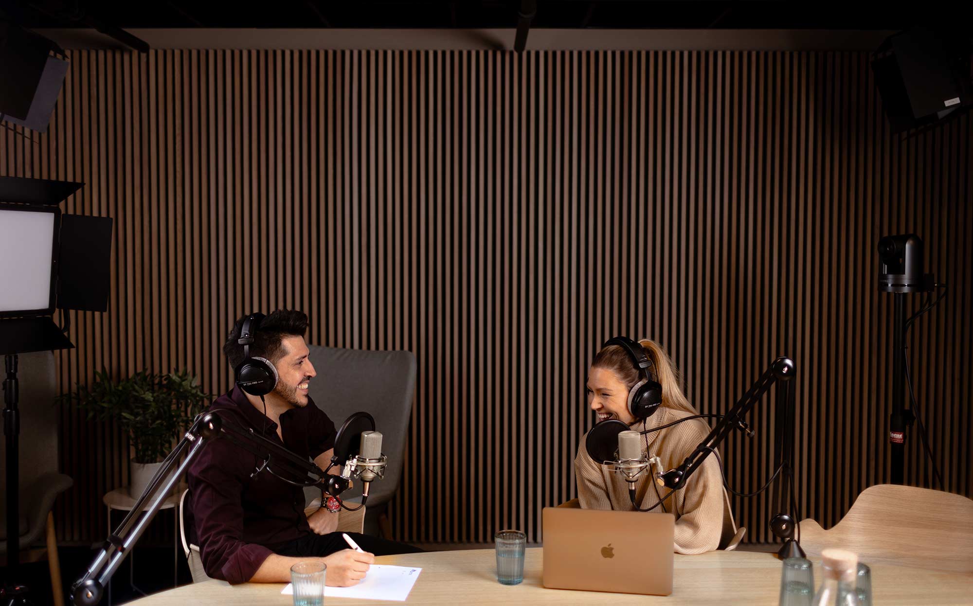 Dame og mann sitter i podcaststudio i Skullerud Park og ler